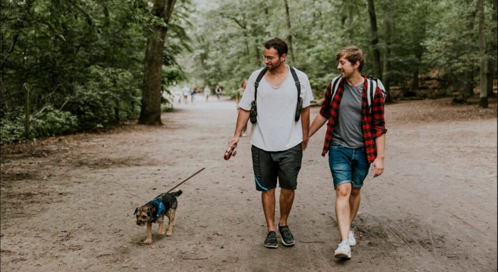 two men walking with one dog and slightly smiling | make money pet sittng